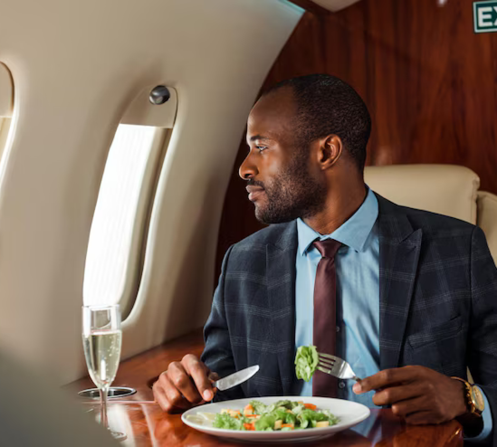 handsome-african-american-businessman-holding-cutlery-near-salad-private-jet_824701-13723